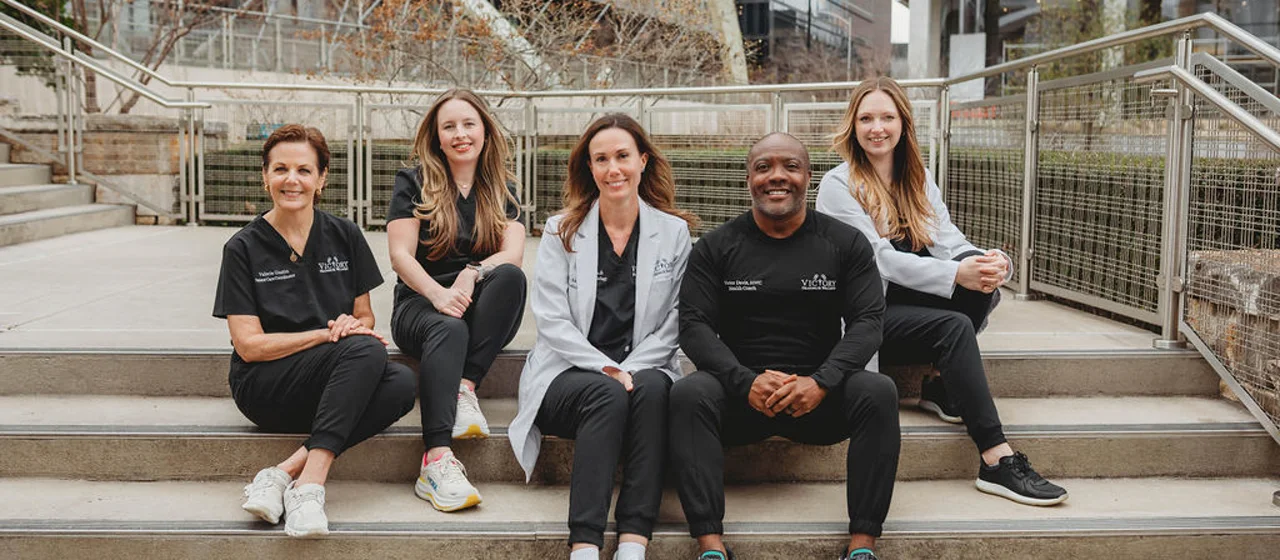 The Victory Health & Wellness care team seated together on outdoor steps in Austin